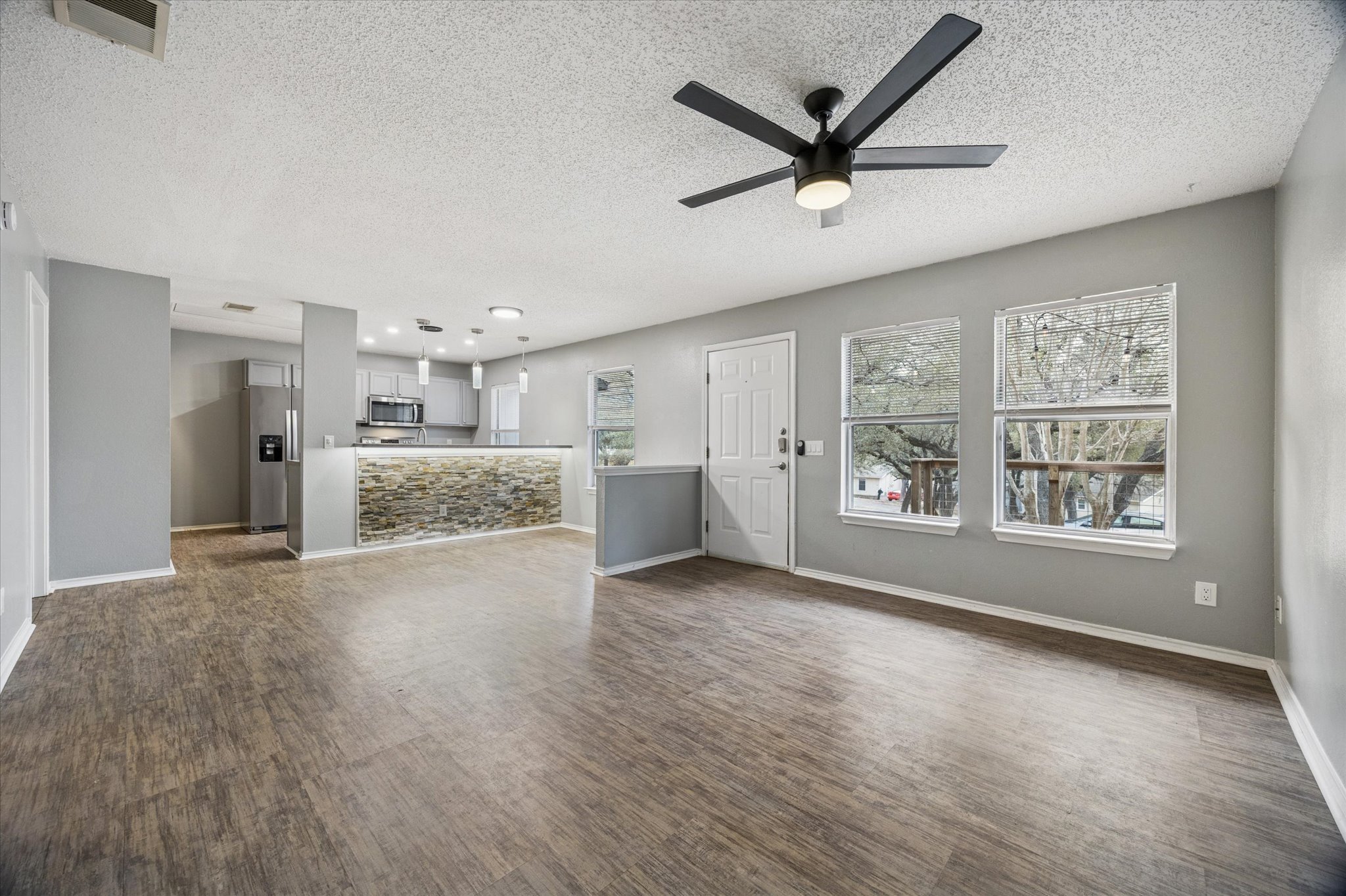 23393 Nameless Road, Unit 152 Leander, TX 78641 - Photo 4 of 10 Unfurnished living room with dark wood finished floors, a ceiling fan, and a textured ceiling