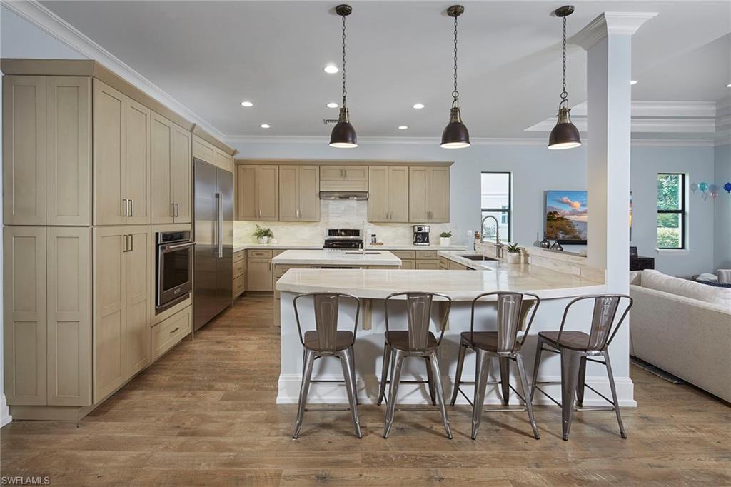 2863 Coco Lakes Drive Naples, FL 34105 - Photo 5 of 39 a kitchen with stainless steel appliances kitchen island granite countertop a dining table chairs and a refrigerator