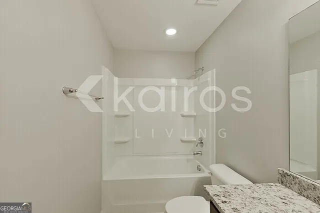 a bathroom with a granite countertop sink a toilet and shower