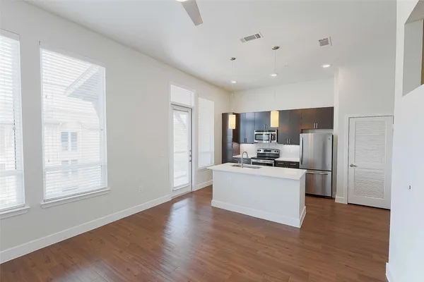 a kitchen with stainless steel appliances a refrigerator and wooden floor