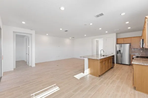 a large kitchen with stainless steel appliances a large counter top a stove and a refrigerator