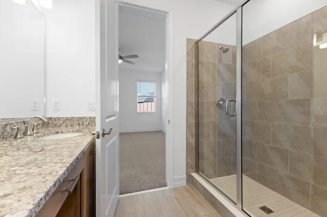 a bathroom with a granite countertop shower a mirror and a sink