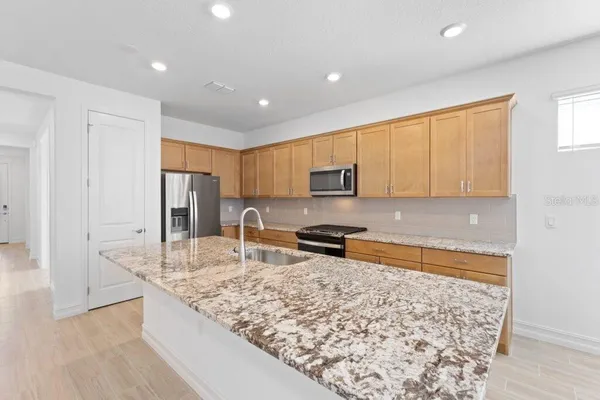 a kitchen with stainless steel appliances granite countertop a sink stove and refrigerator