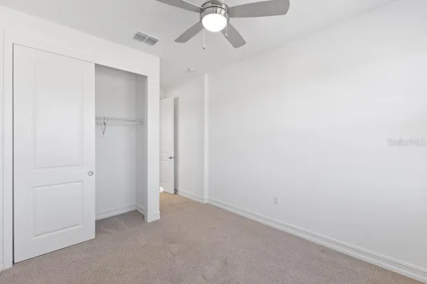 an empty room with closet and a chandelier fan