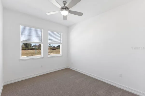 an empty room with a window and a fan