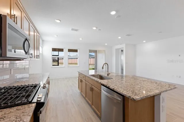 a kitchen with stainless steel appliances granite countertop a sink stove and cabinets
