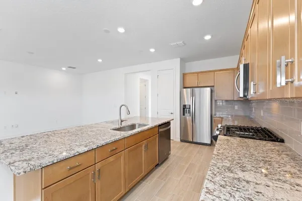 a kitchen with stainless steel appliances granite countertop a sink stove and refrigerator