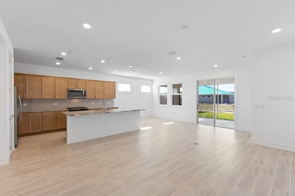 a view of large kitchen with stainless steel appliances granite countertop a stove and a wooden floors