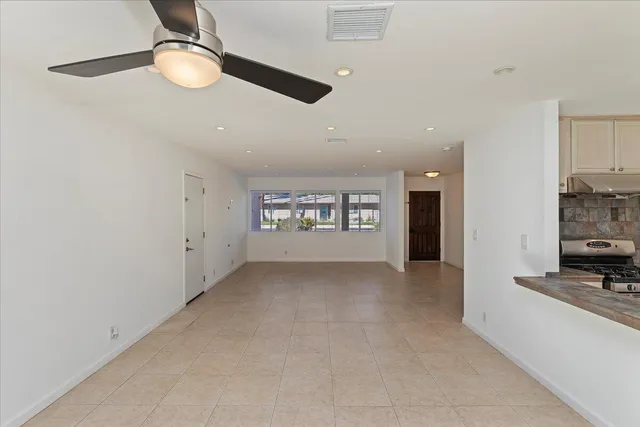 a view of an empty room with a window and kitchen view