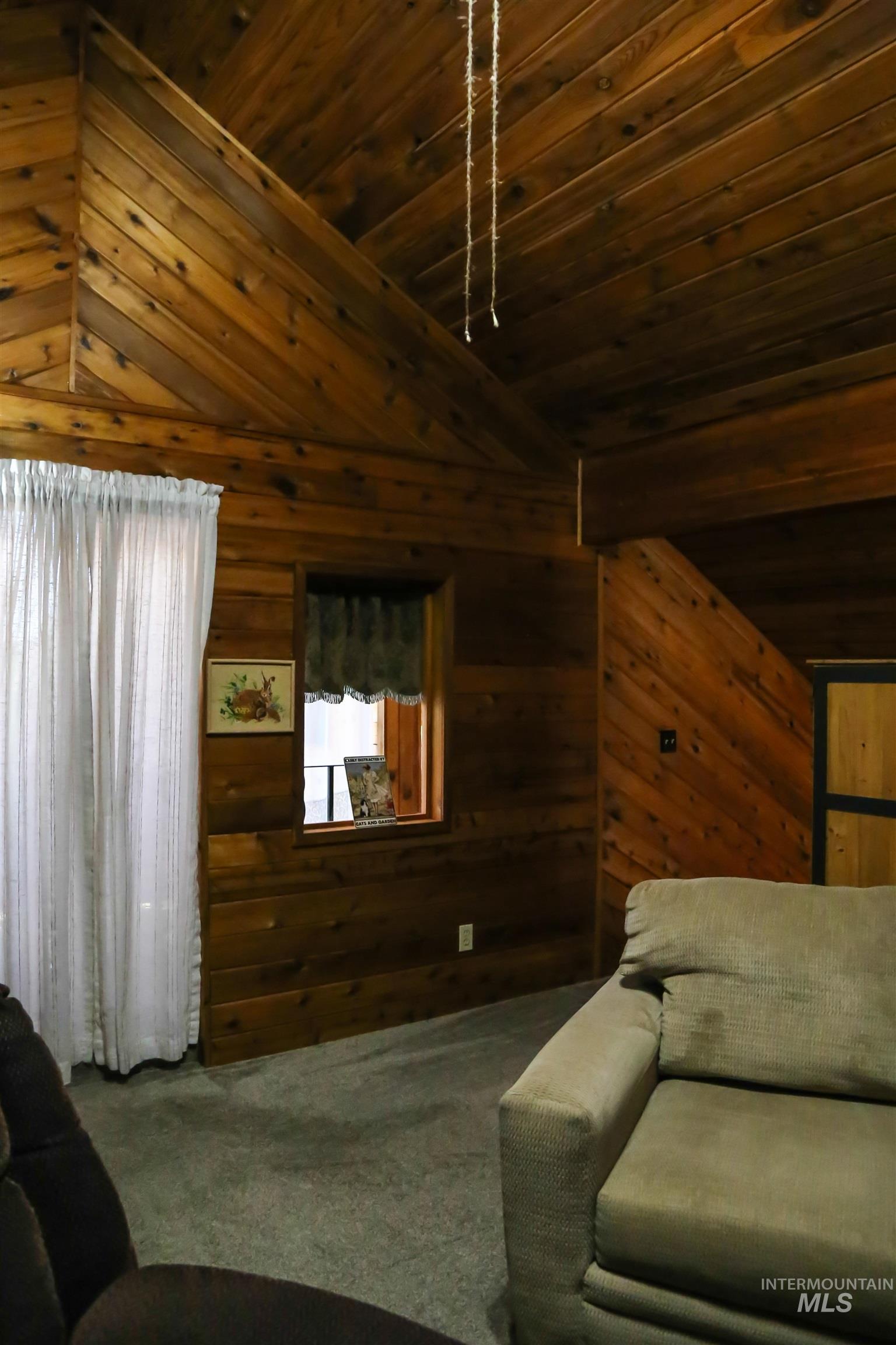 2060 Missman Road Council, ID 83612 - Photo 16 of 50 Living area with dark colored carpet, wooden walls, and a vaulted wooden ceiling