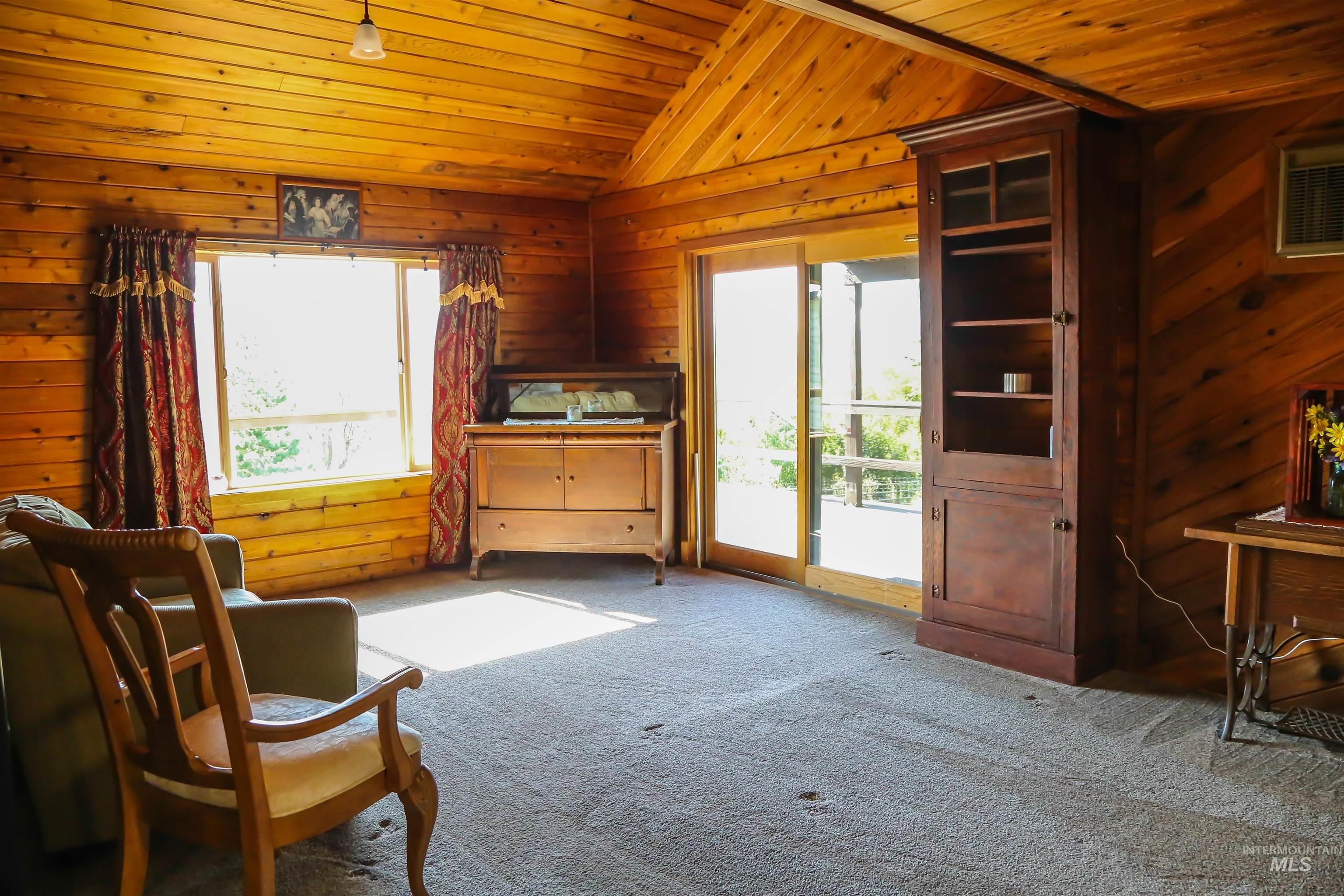 2060 Missman Road Council, ID 83612 - Photo 4 of 50 Living area with a vaulted wood ceiling, wood walls, and carpet