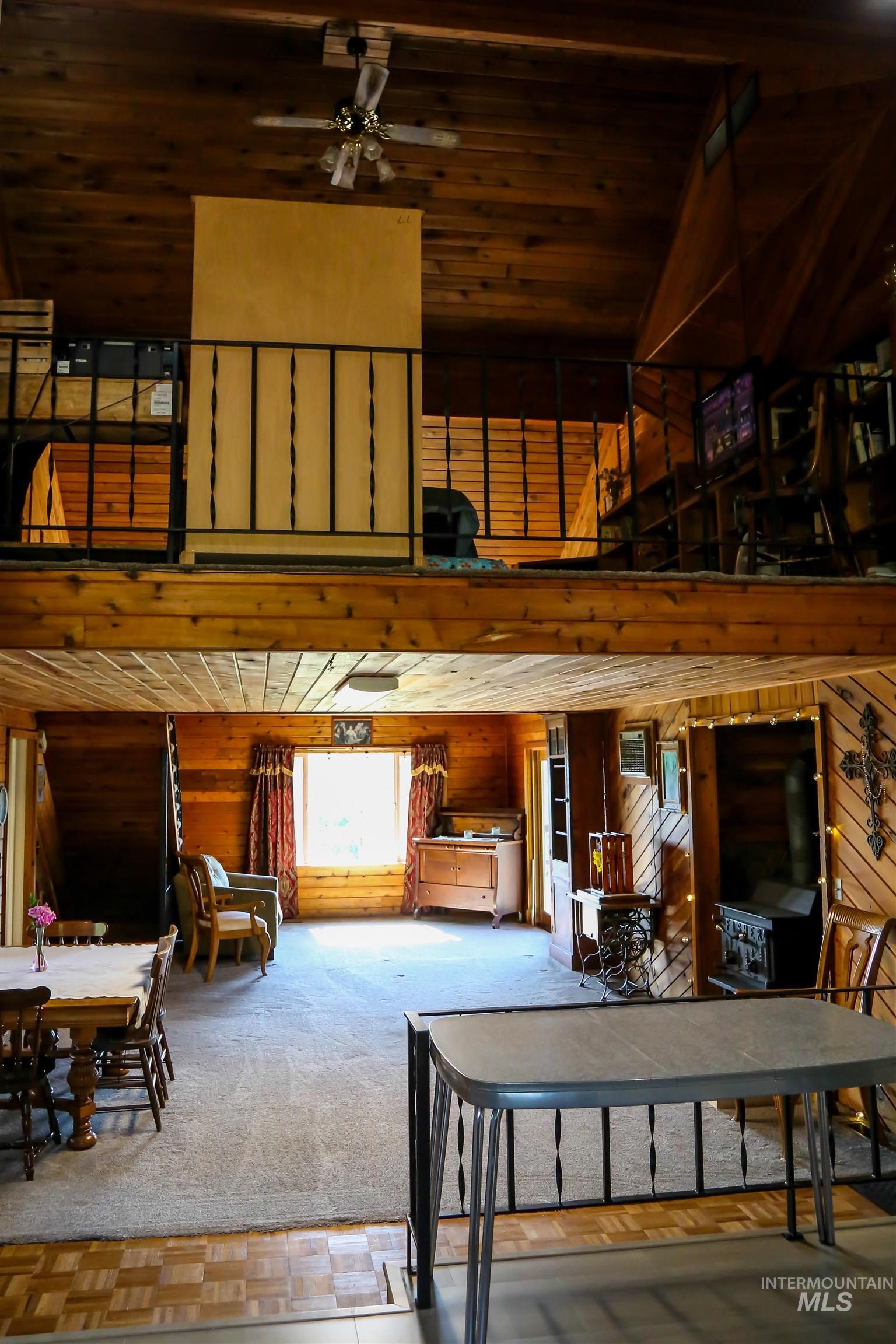 2060 Missman Road Council, ID 83612 - Photo 8 of 50 Living area with a vaulted wood ceiling, wood walls, a ceiling fan, and carpet floors