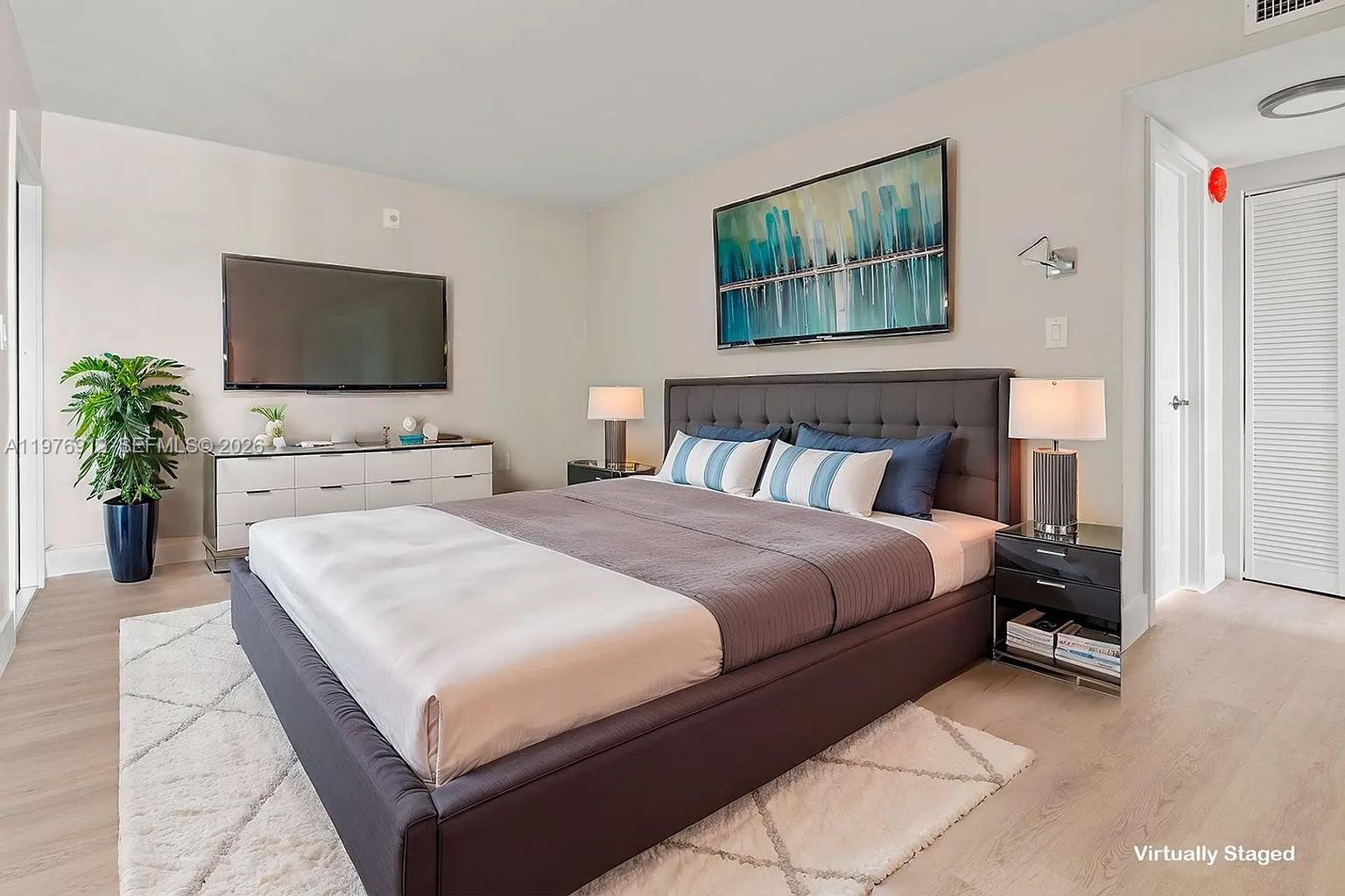 1101 Northeast 80th Street, Unit 201 Miami, FL 33138 - Photo 3 of 17 a bedroom with a large bed and a flat screen tv