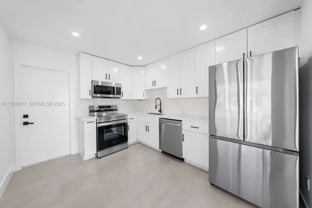 a kitchen with white cabinets and stainless steel appliances