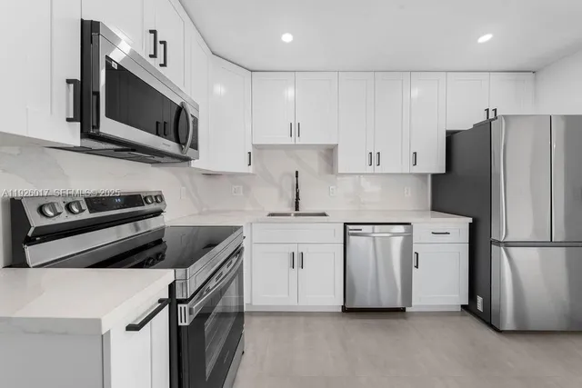 a kitchen with stainless steel appliances a refrigerator a stove top oven a sink and cabinets