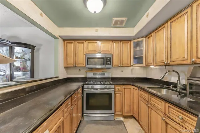 a kitchen with granite countertop a stove sink and microwave