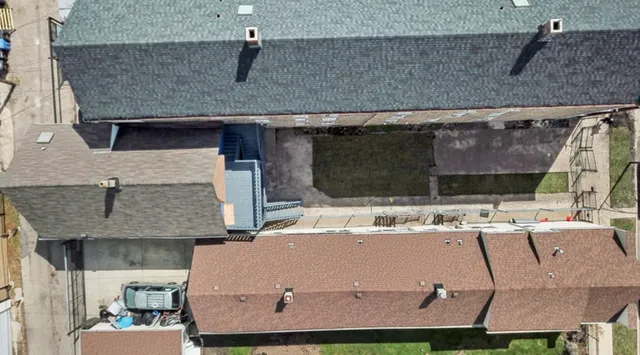 a view of a white house next to a yard and road