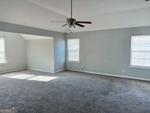 an empty room with windows and fan