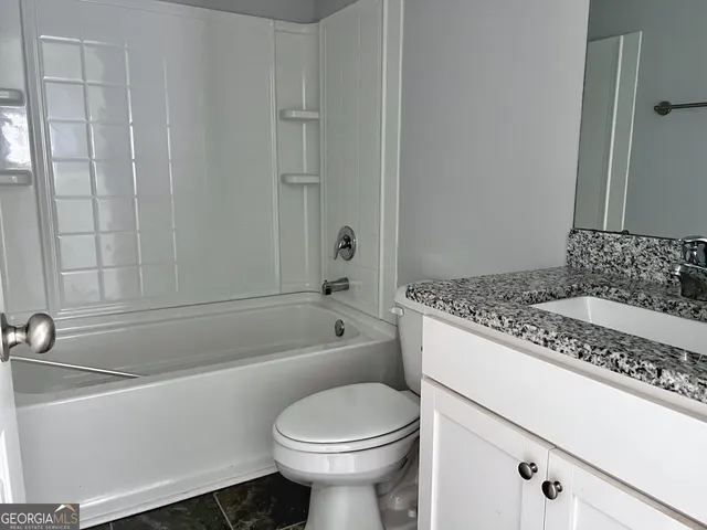 a bathroom with a granite countertop sink a toilet and bathtub