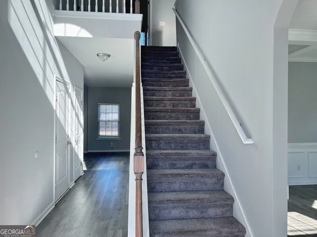 a view of staircase with wooden floor and white walls