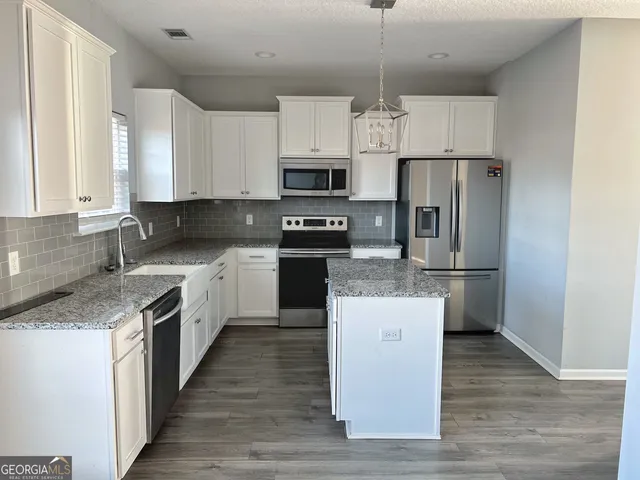 a kitchen with stainless steel appliances granite countertop a refrigerator a stove top oven a sink and dishwasher with wooden floor