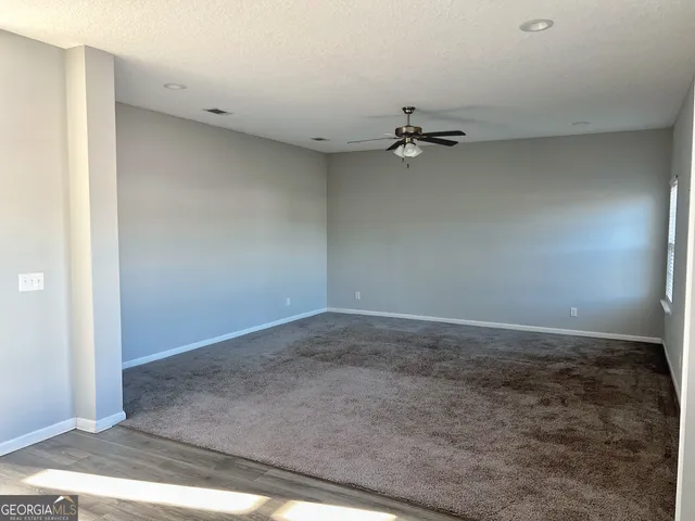 an empty room with a ceiling fan and carpet