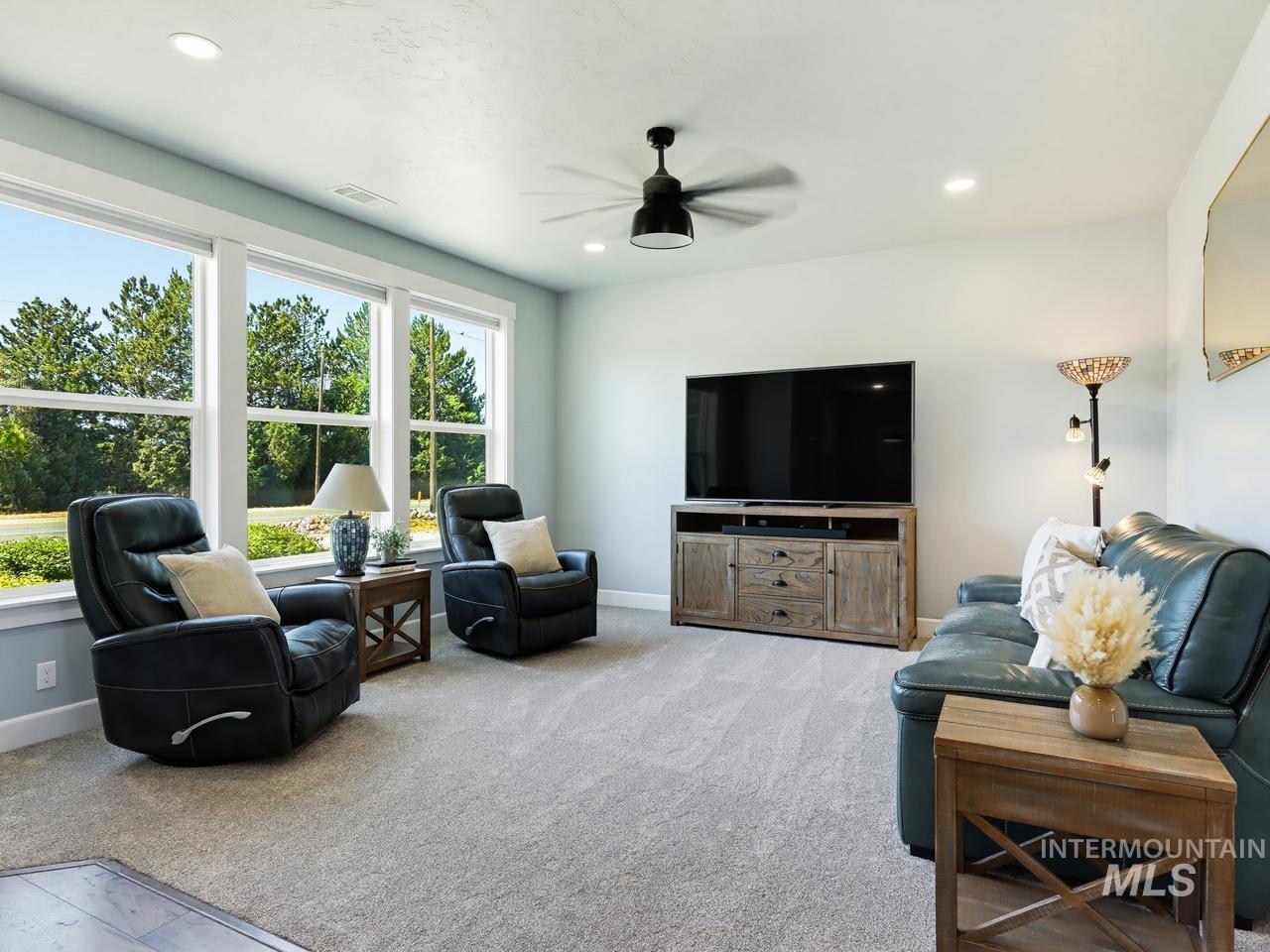 4950 West Columbia Road Nampa, ID 83687 - Photo 8 of 50 Wall of windows with white trim, recessed lighting, ceiling fan, and carpeted flooring