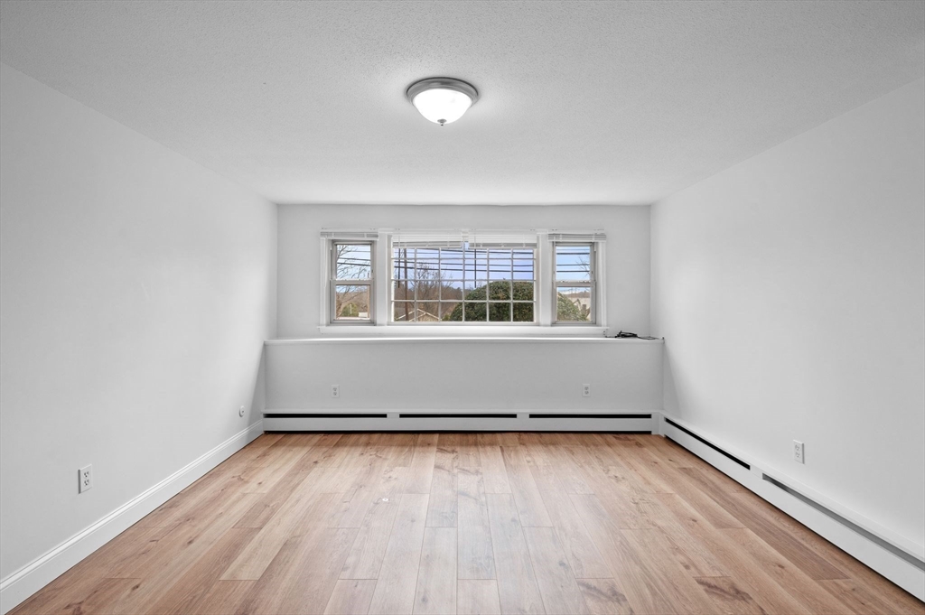 121 Cambridge Road, Unit 2 Woburn, MA 01801 - Photo 5 of 23 an empty room with wooden floor and windows