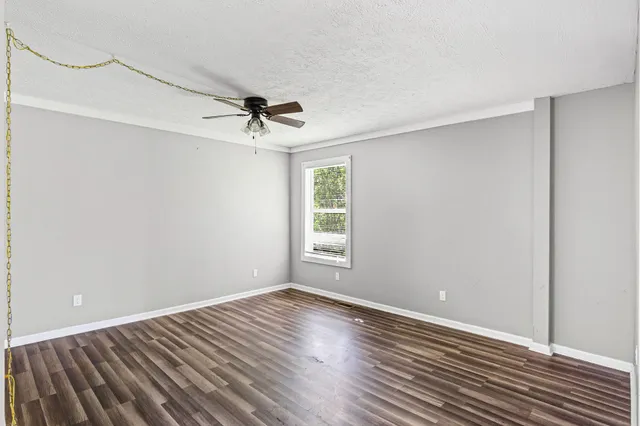 a view of a room with wooden floor a ceiling fan and windows