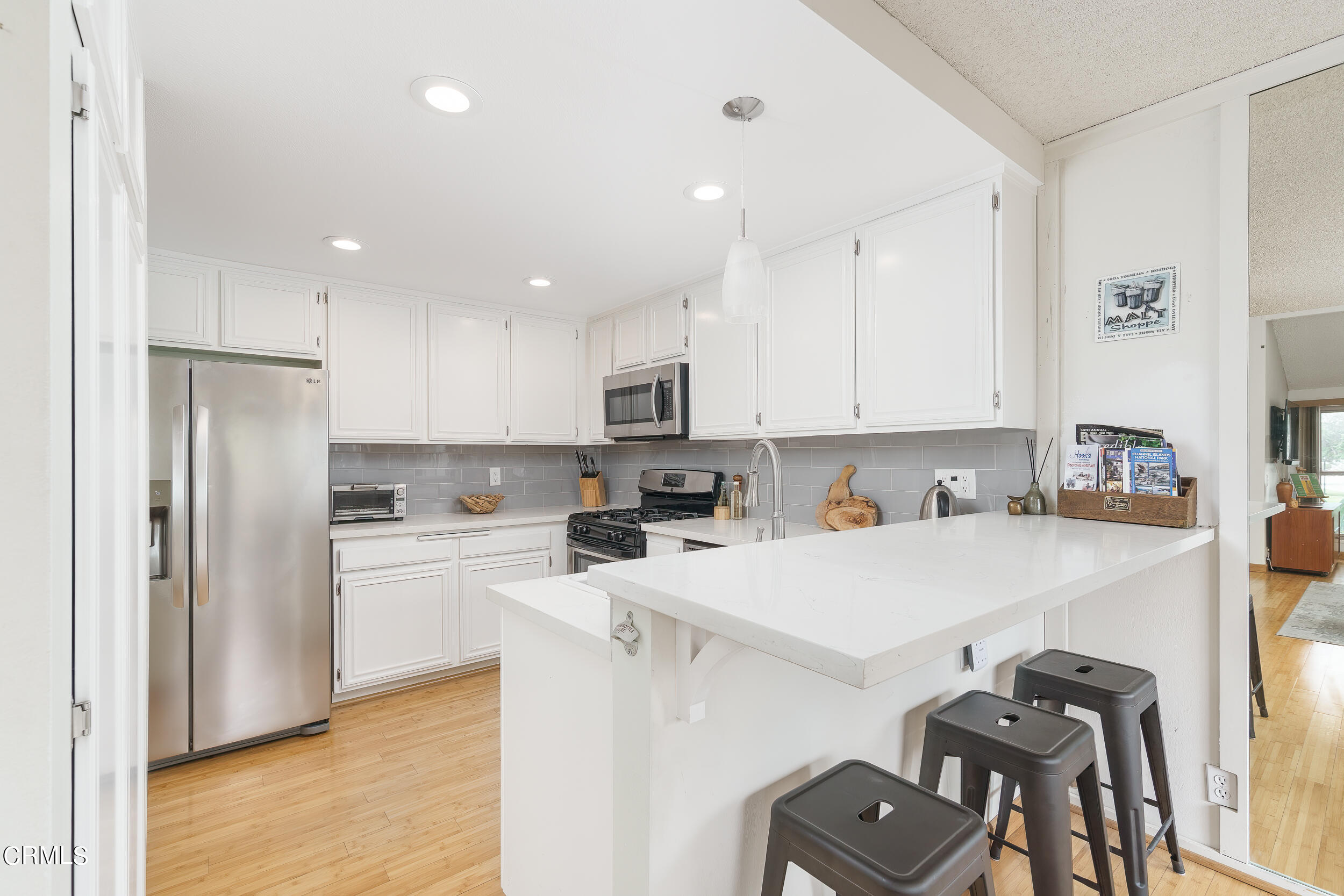 3225 Harbor Boulevard Oxnard, CA 93035 - Photo 8 of 34 a kitchen with a refrigerator a white stove top oven a sink and white cabinets with wooden floor