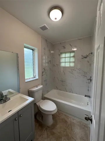 a bathroom with a bathtub toilet sink vanity and windows
