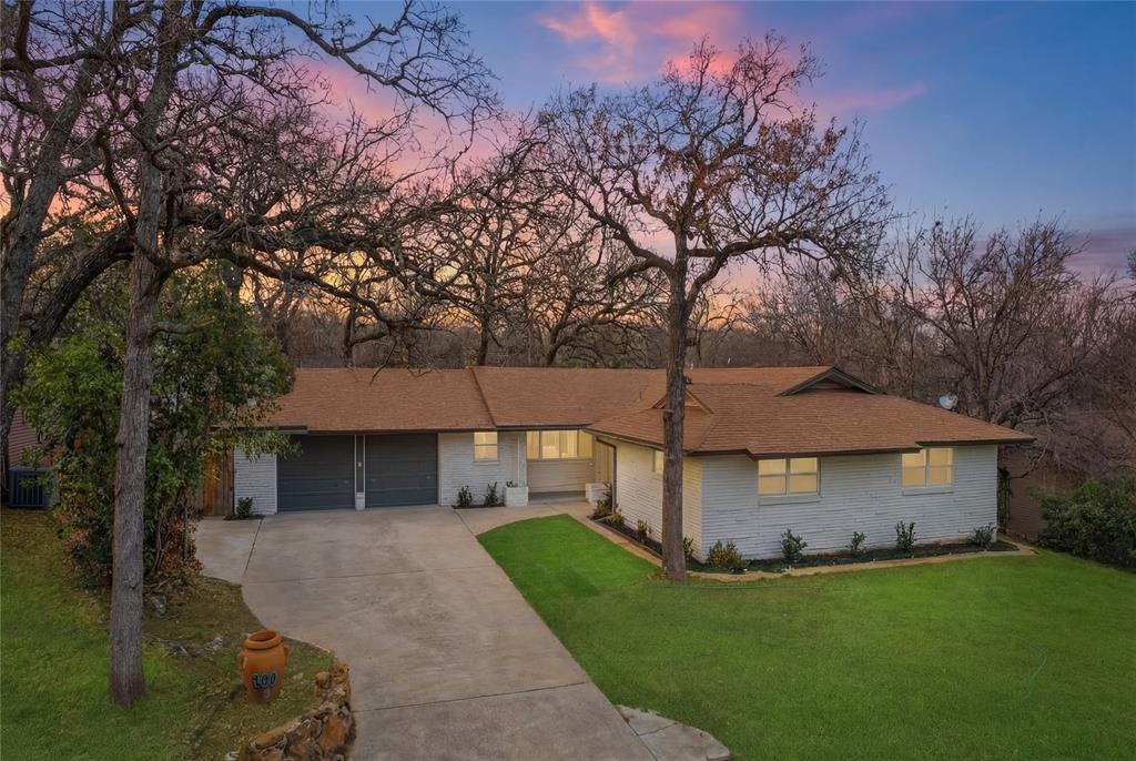 Ranch-style home with concrete driveway, a lawn, brick siding, and roof with shingles