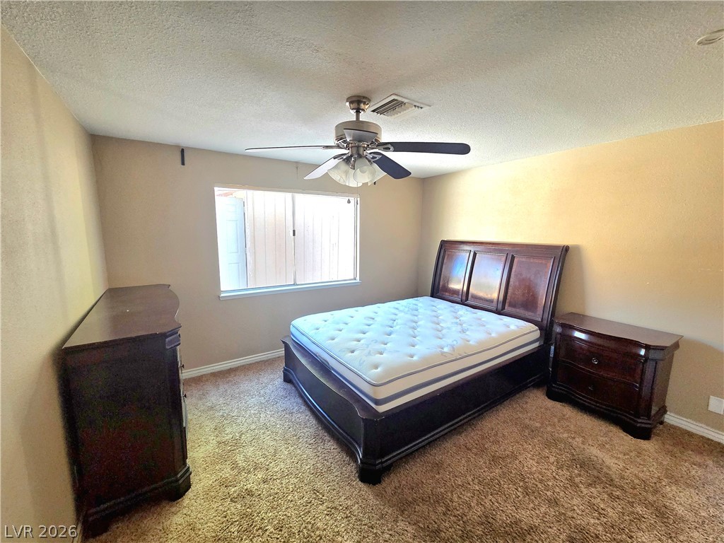 3648 Bronco Road Las Vegas, NV 89103 - Photo 12 of 24 A comfortable bedroom features plush carpeting and a cooling ceiling fan.