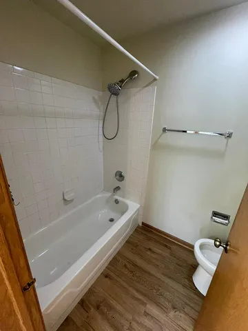 a bathroom with a tub a sink and wooden floor