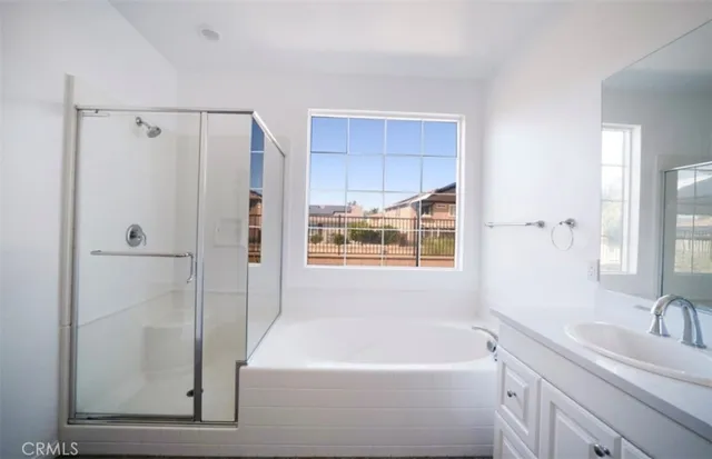 a bathroom with a tub a sink a window and a shower