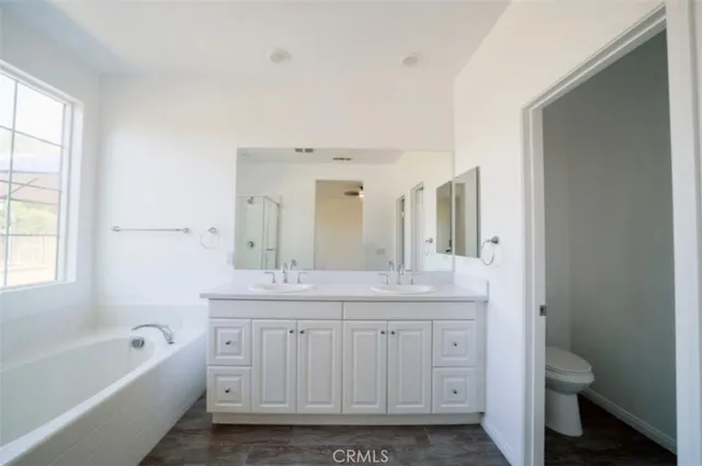 a spacious bathroom with a granite countertop sink a toilet mirror and bathtub