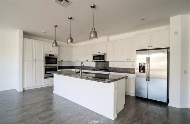 a kitchen with stainless steel appliances granite countertop a refrigerator a sink a stove and white cabinets