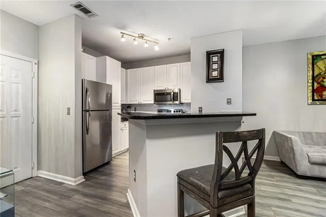 a kitchen with stainless steel appliances kitchen island a table chairs refrigerator and a sink