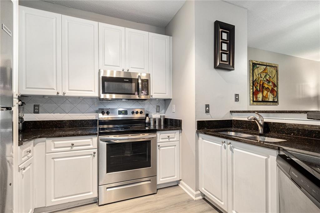 10 Perimeter Summit Boulevard, Unit 4131 Atlanta, GA 30319 - Photo 18 of 30 a kitchen with stainless steel appliances granite countertop a stove a microwave and a white cabinets