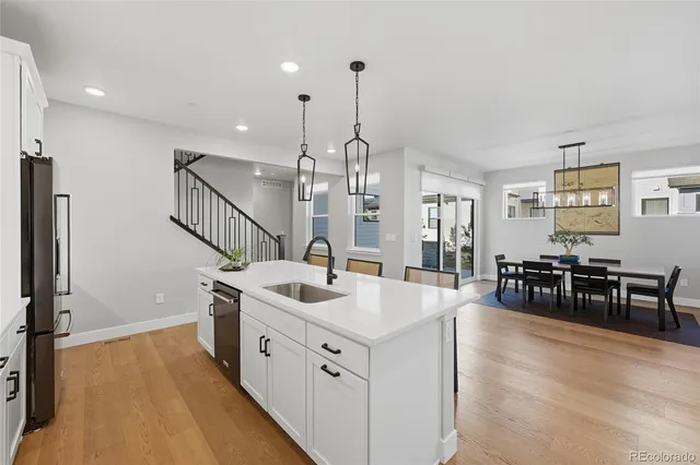 a kitchen with stainless steel appliances granite countertop a sink a oven a dining table and chairs with wooden floor