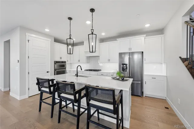 a kitchen with stainless steel appliances a dining table chairs refrigerator and microwave