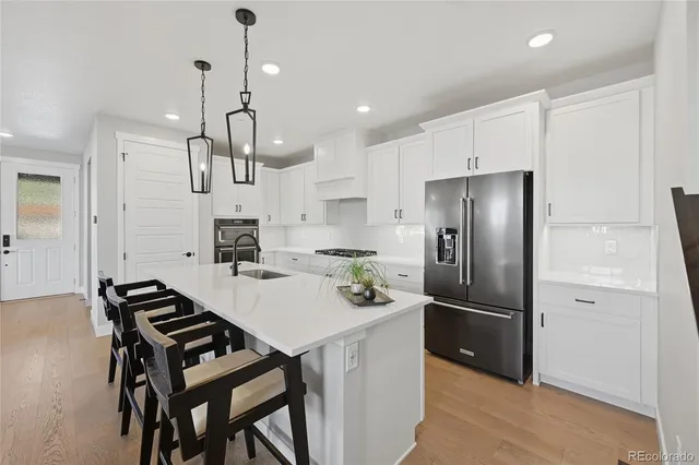 a kitchen with stainless steel appliances a refrigerator a sink a stove a table and chairs