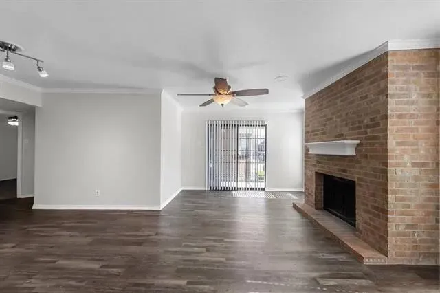 a view of an empty room with wooden floor fireplace and a window