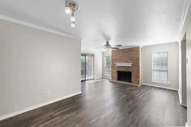 an empty room with wooden floor fireplace and chandelier fans