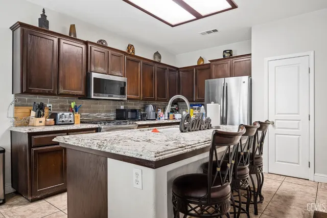 a kitchen with stainless steel appliances a stove a sink a microwave a refrigerator and cabinets