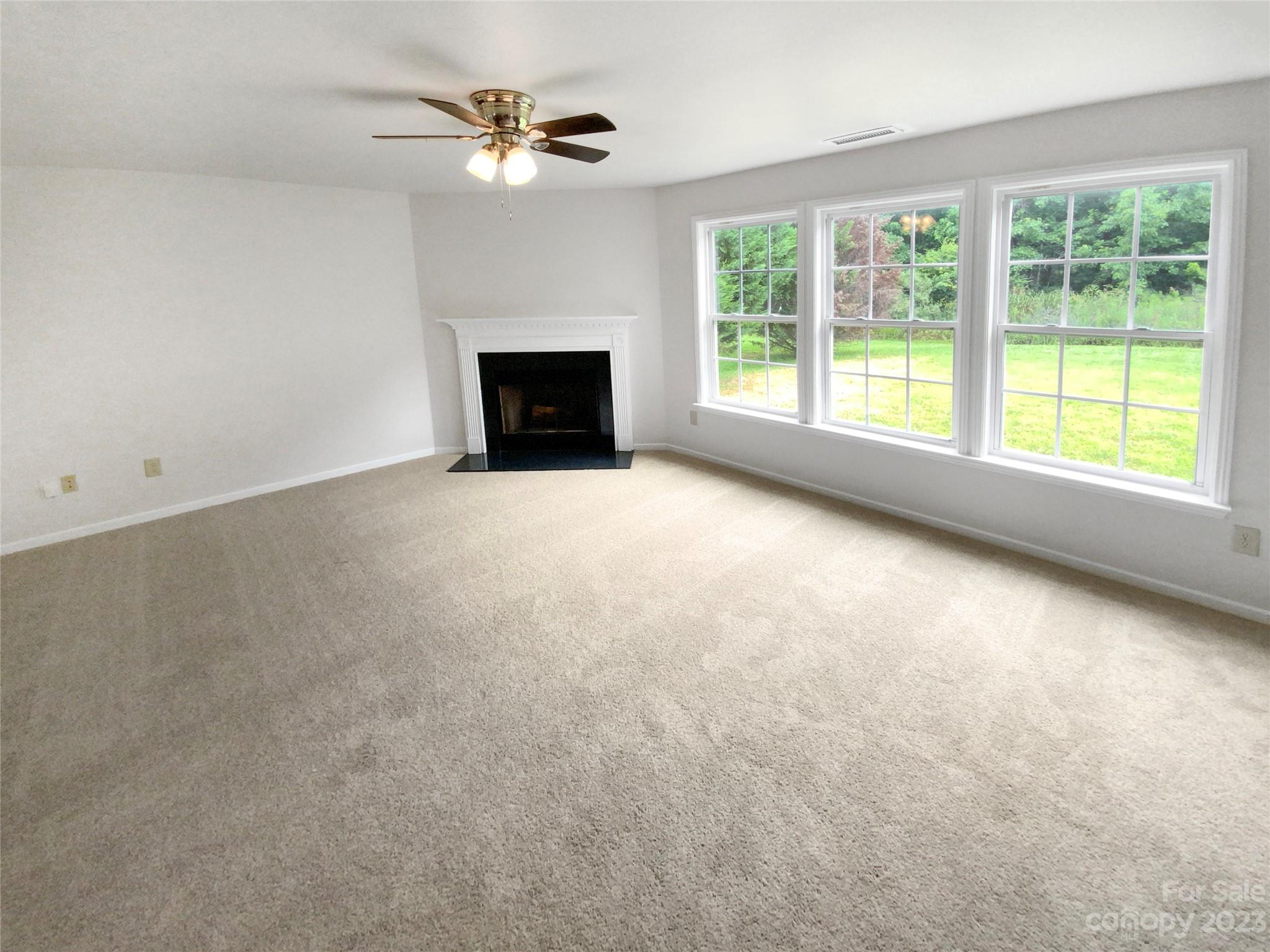 2518 Spring Breeze Way Monroe, NC 28110 - Photo 3 of 22 an empty room with windows chandelier fan and fireplace