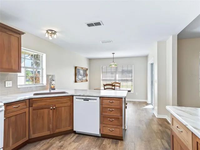 a kitchen with kitchen island granite countertop a sink cabinets and wooden floor