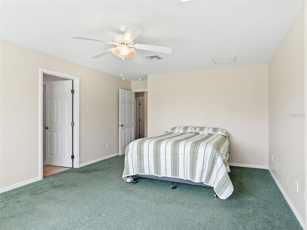 12321 Southeast 176th Loop Summerfield, FL 34491 - Photo 20 of 51 a spacious bedroom with a bed and a chandelier