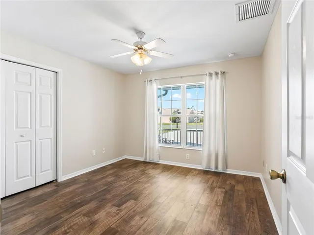 a view of an empty room with a window and wooden floor