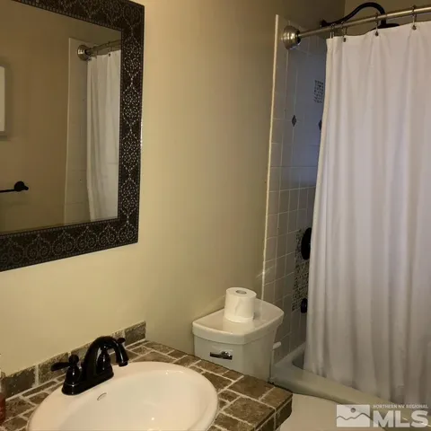 a bathroom with a sink a toilet and shower curtain